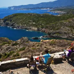 Disfrutando de la vista del Cap de Creus, con sus calas y montañas, mientras la gente descansa en sillas.