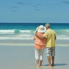 Pareja mayor disfrutando de sus viajes El Corte Inglés mayores 60 años en una playa paradisíaca.