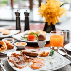 Desayuno completo con huevos, salchichas, tocino y jugo de naranja. ¡Ideal para empezar el día de tu vuelo+hotel todo incluido baratos!