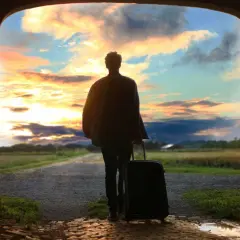 Persona con maleta, lista para viajar, ante un atardecer espectacular. ¡Aprovecha las ofertas viajes última hora 2x1!