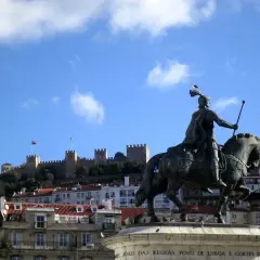 Estatua ecuestre de un rey con el Castillo de San Jorge al fondo, un lugar que ver en Lisboa.
