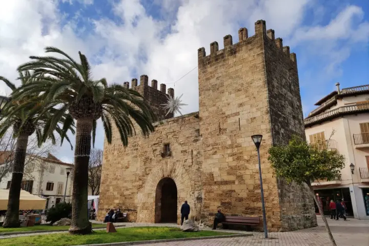 Puerta de Alcudia, Valencia, con palmeras y cielo azul.