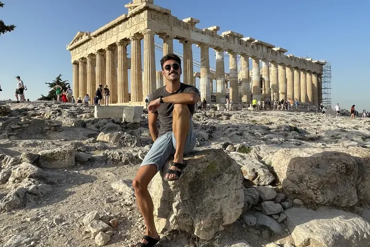 Hombre sentado en la Acrópolis, disfrutando de la vista del Partenón. ¡Una parada obligatoria si buscas qué ver en Atenas en 2 días!