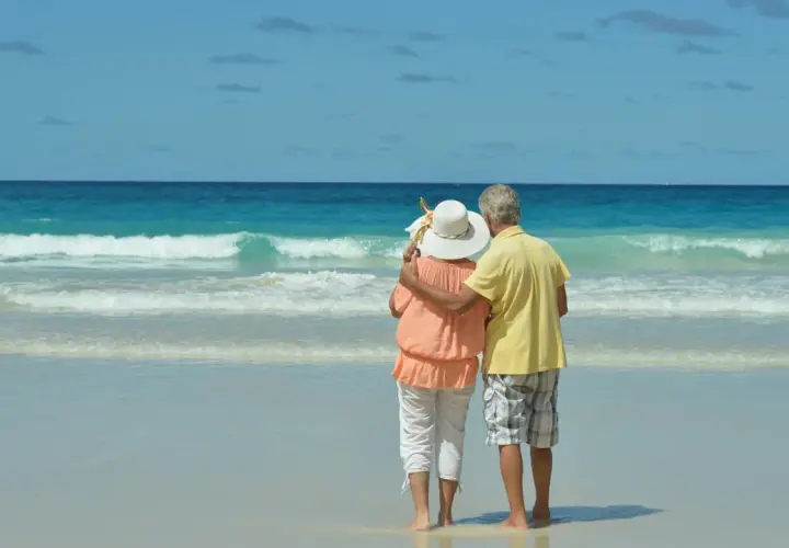 Pareja mayor disfrutando de sus viajes El Corte Inglés mayores 60 años en una playa paradisíaca.