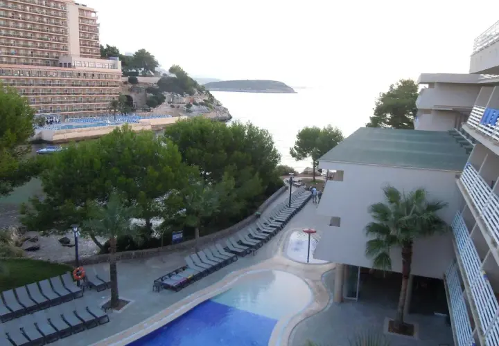 Resort con piscina y tumbonas junto al mar, con vistas a la costa de occidental cala viñas.