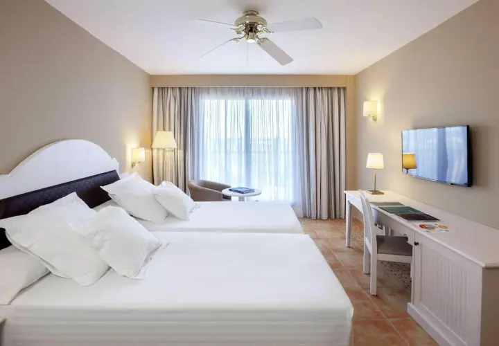 Habitación doble con camas blancas y escritorio en el hotel Occidental Isla Cristina.