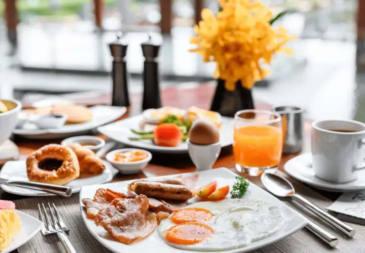 Desayuno completo con huevos, salchichas, tocino y jugo de naranja. ¡Ideal para empezar el día de tu vuelo+hotel todo incluido baratos!