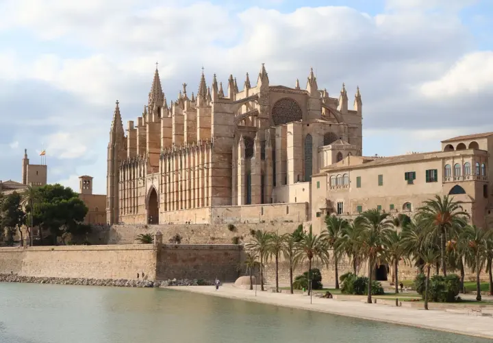 La Catedral de Mallorca, un impresionante edificio gótico, se alza majestuosa junto al mar, evocando la grandeza de Barcelona.