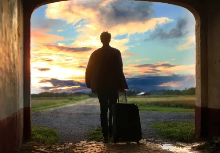Persona con maleta, lista para viajar, ante un atardecer espectacular. ¡Aprovecha las ofertas viajes última hora 2x1!