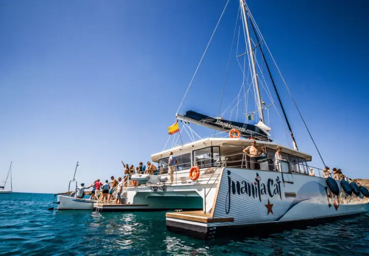 Catamarán "Juanita Cat" listo para el ferry Lanzarote La Graciosa. Turistas disfrutan del sol y el mar azul.