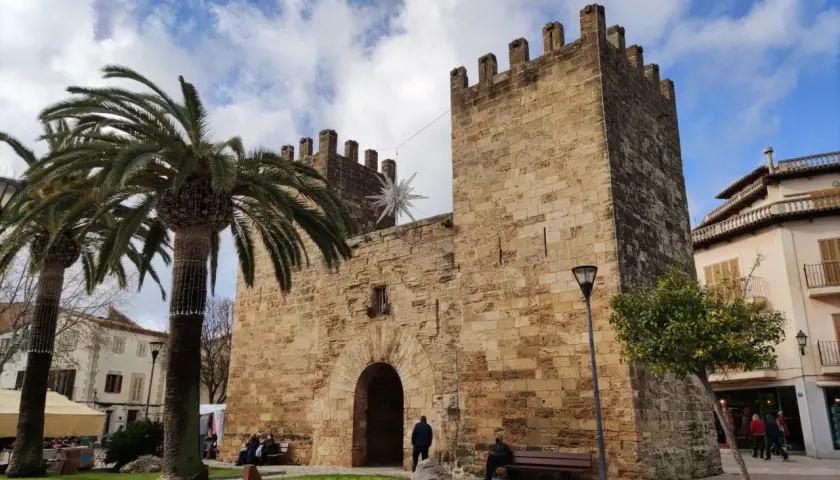 Puerta de Alcudia, Valencia, con palmeras y cielo azul.