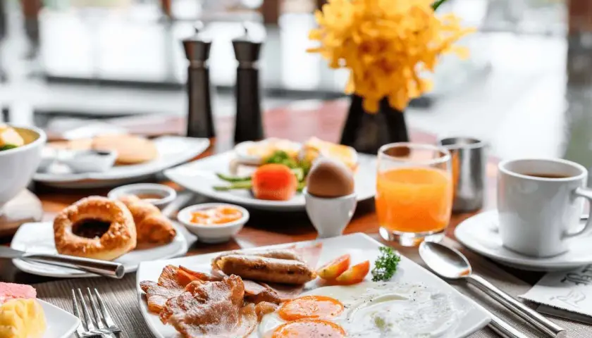 Desayuno completo con huevos, salchichas, tocino y jugo de naranja. ¡Ideal para empezar el día de tu vuelo+hotel todo incluido baratos!