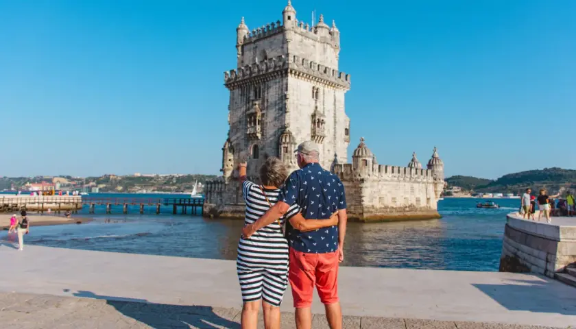 Pareja disfrutando de sus vacaciones en Portugal, admirando la Torre de Belém en Lisboa.