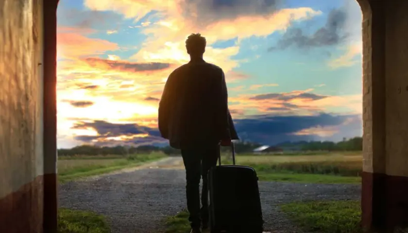 Persona con maleta, lista para viajar, ante un atardecer espectacular. ¡Aprovecha las ofertas viajes última hora 2x1!