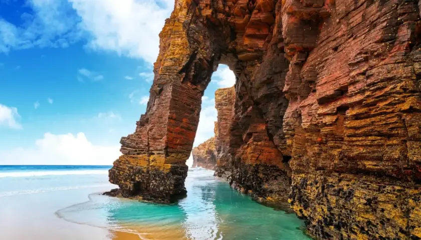 Arco natural en la playa de las Catedrales, un lugar ideal donde viajar en agosto en España.
