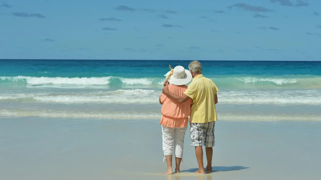 Pareja mayor disfrutando de sus viajes El Corte Inglés mayores 60 años en una playa paradisíaca.