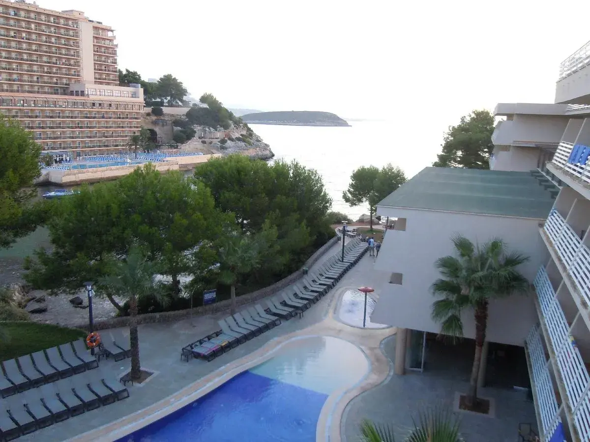 Resort con piscina y tumbonas junto al mar, con vistas a la costa de occidental cala viñas.