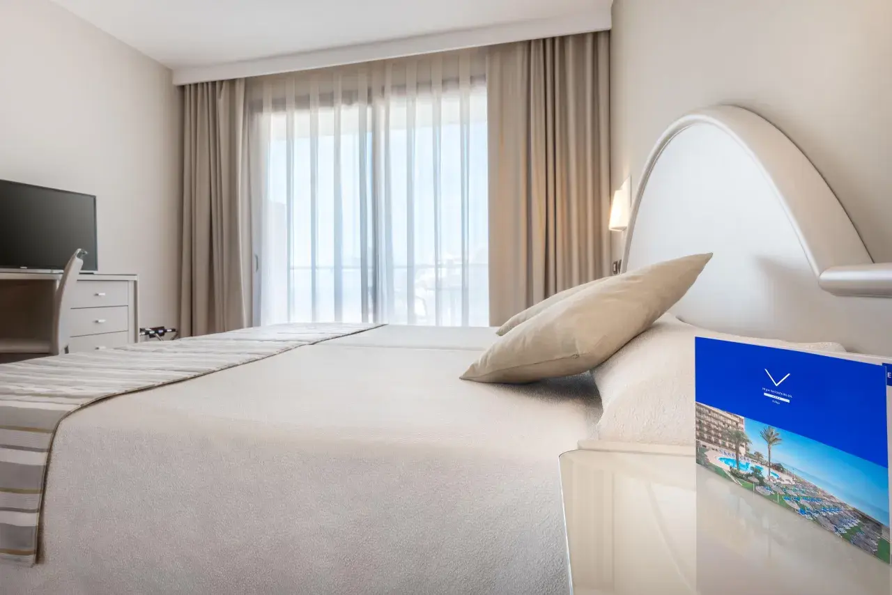Habitación luminosa con cama doble, TV y folleto del Vik Gran Hotel Costa del Sol.