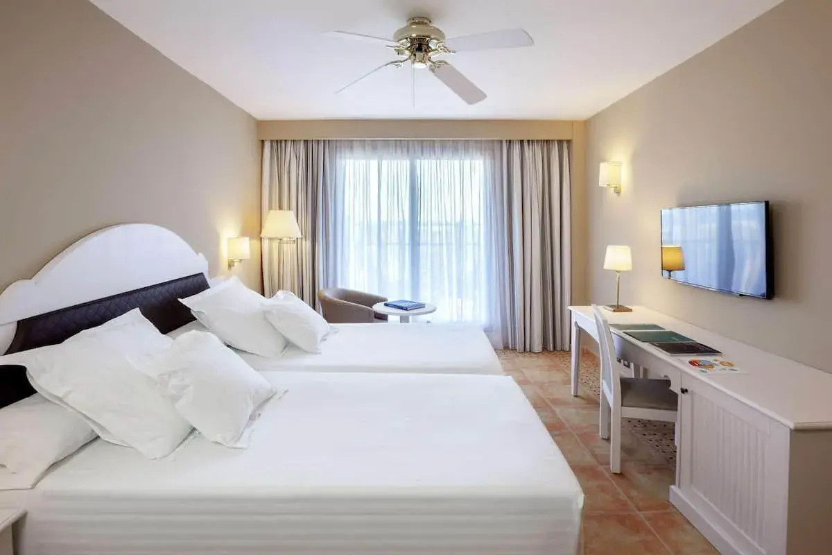Habitación doble con camas blancas y escritorio en el hotel Occidental Isla Cristina.