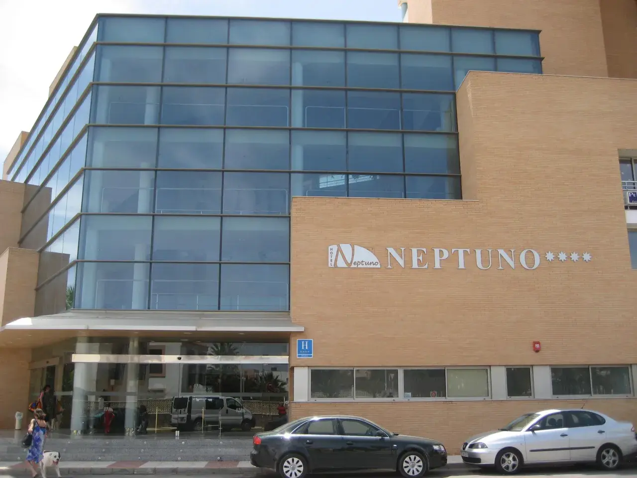 Fachada moderna del hotel Neptuno Roquetas de Mar, con amplios ventanales y detalles en ladrillo.