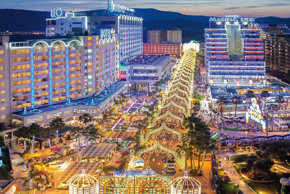 Noche vibrante en Marina d'Or, ciudad de vacaciones, con hoteles iluminados y un paseo lleno de luces y gente.