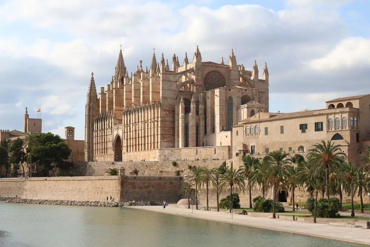 La Catedral de Mallorca, un impresionante edificio gótico, se alza majestuosa junto al mar, evocando la grandeza de Barcelona.