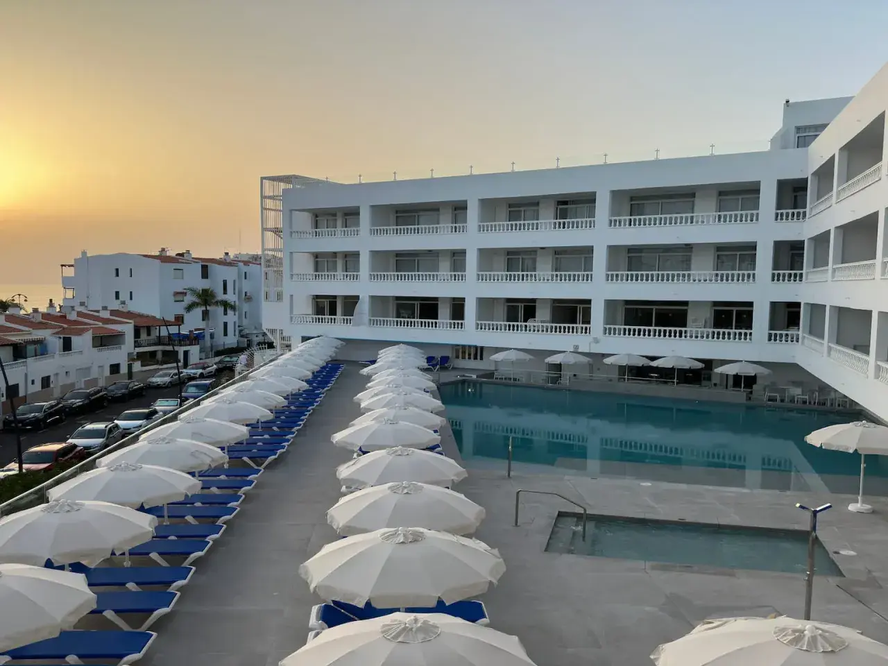 Hotel moderno con piscina y tumbonas, vistas al mar y al atardecer. El azul mar de Lagos de César invita al descanso.