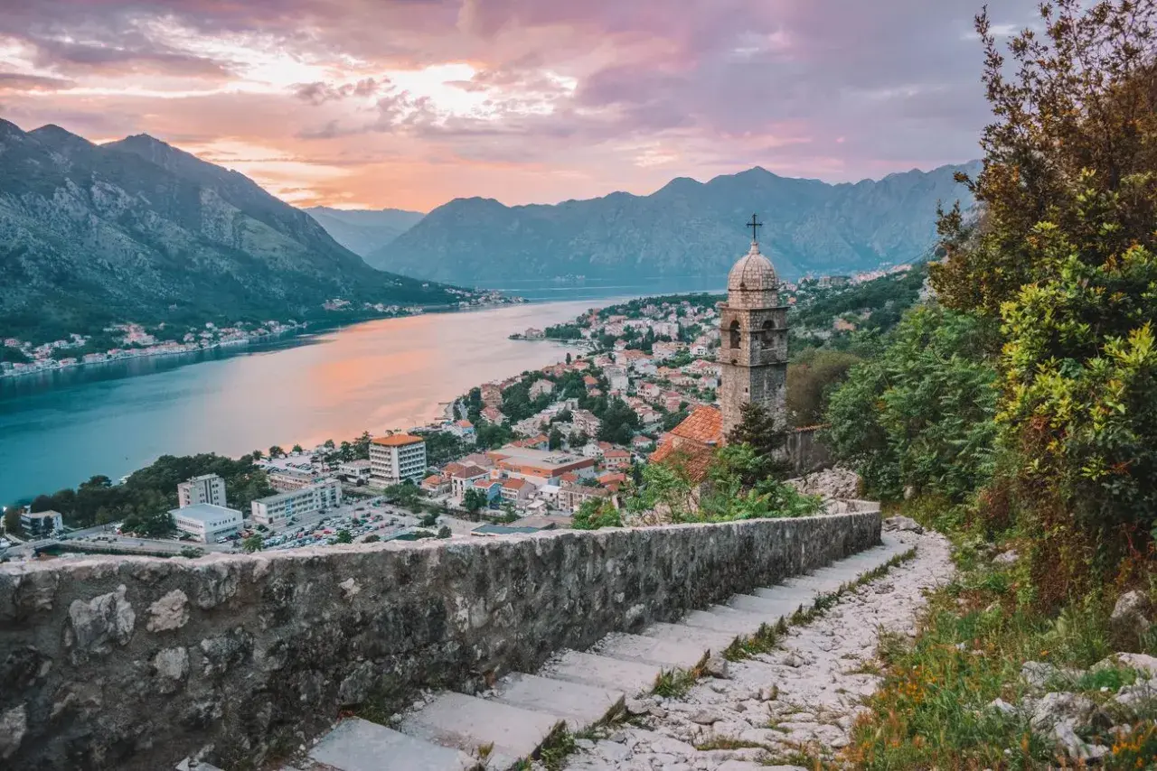 Escaleras de piedra con vistas a la bahía de Kotor al atardecer. Un lugar ideal donde viajar en julio barato.