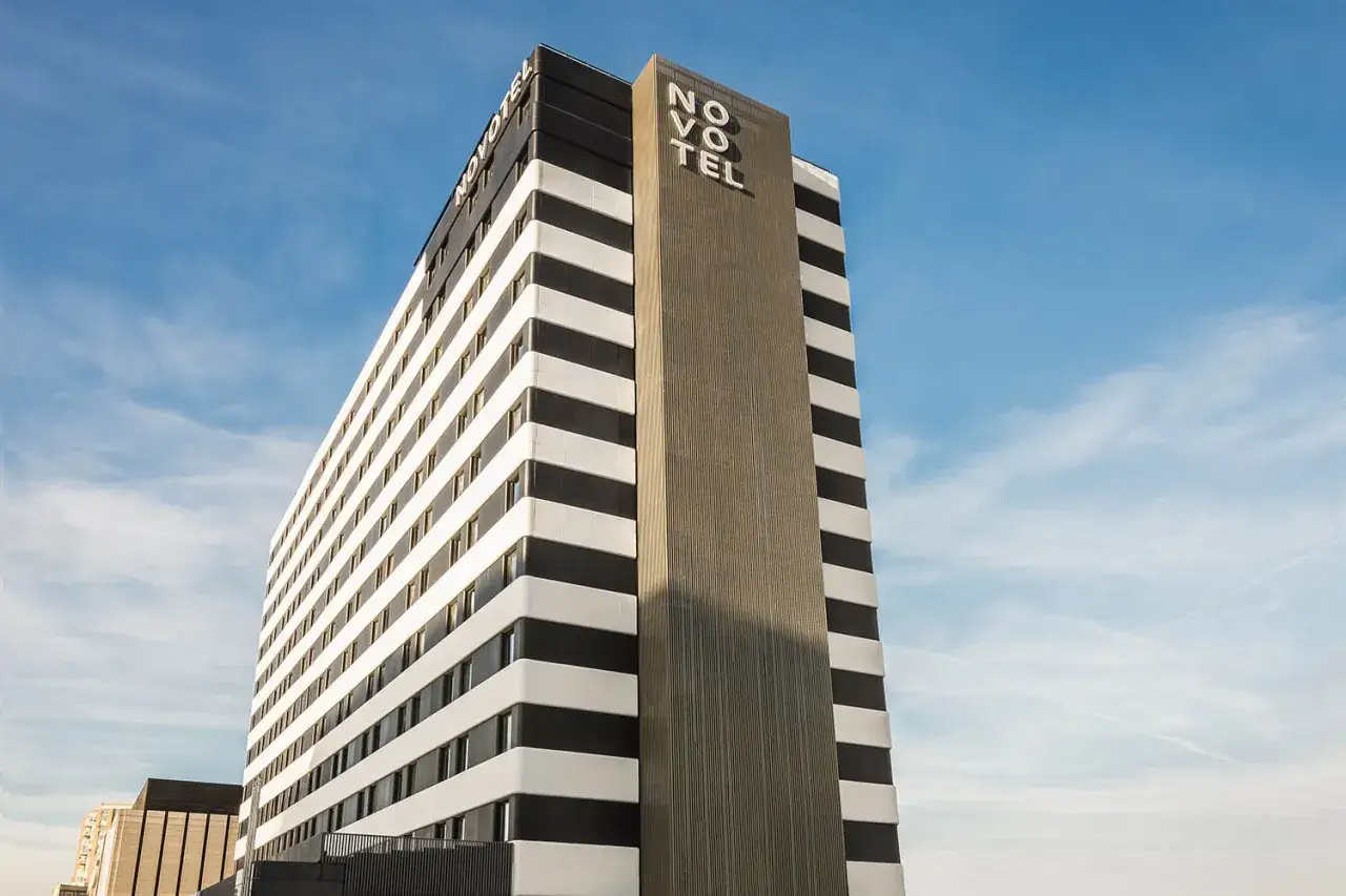 Edificio moderno con franjas blancas y negras, y el logo de Novotel Valencia en la parte superior.