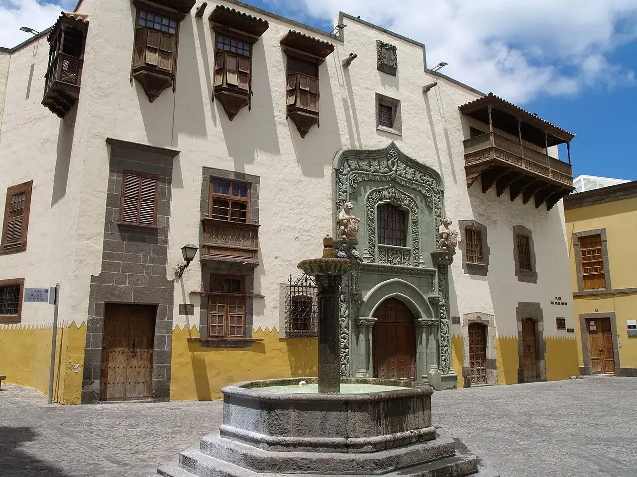 Fuente en plaza de Vegueta, Las Palmas, con arquitectura tradicional canaria y balcones de madera.