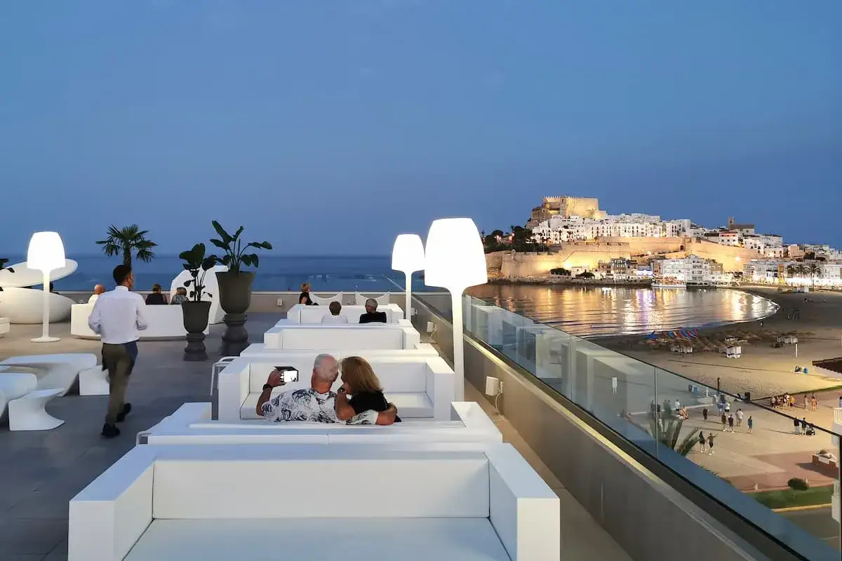Terraza de un hotel con vistas al castillo de Peñíscola. Pareja se toma un selfie.