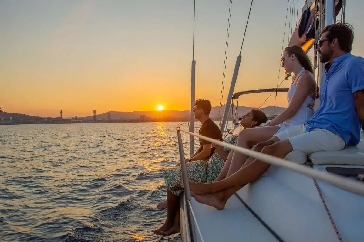 Cuatro amigos disfrutan de un atardecer en velero, inspirando frases de viajes.