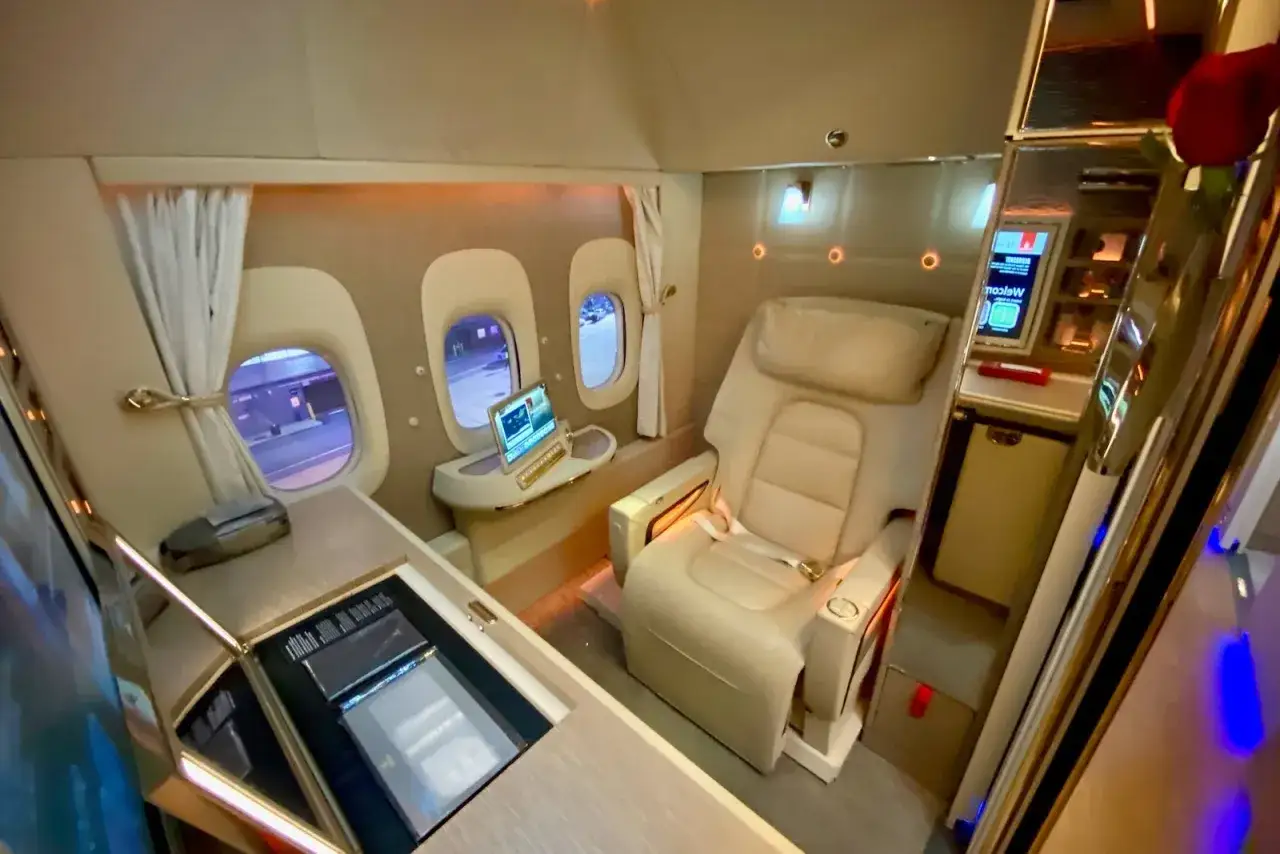 Cabina de business class de lujo con asiento reclinable, pantalla y minibar.