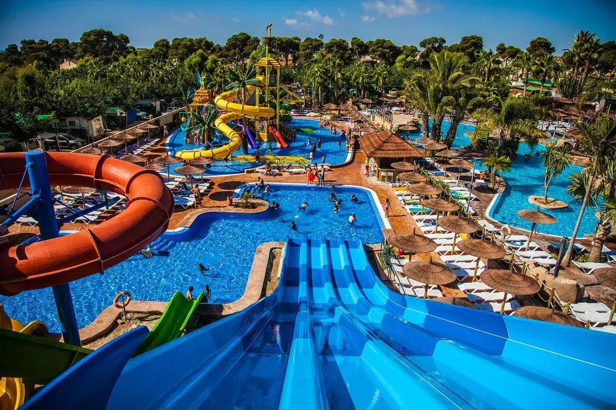 Un resort todo incluido con toboganes acuáticos, piscinas y gente disfrutando del sol.