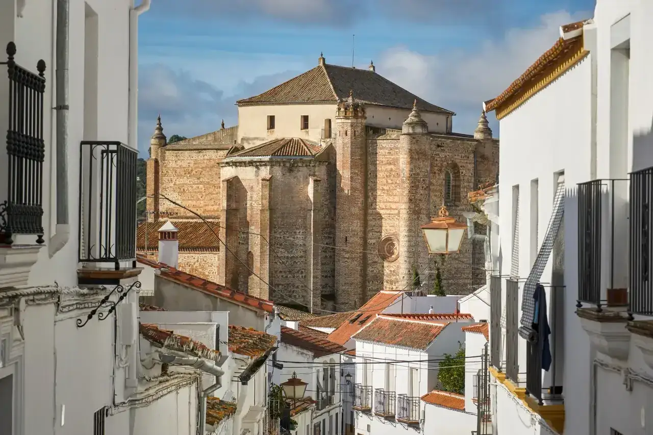 Callejuela blanca en Cazalla de la Sierra con una imponente iglesia de piedra al fondo.