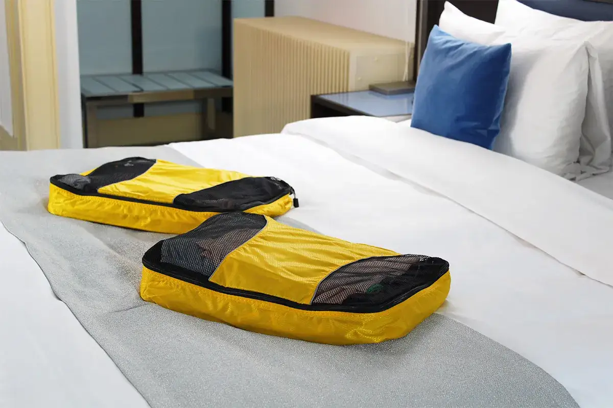 Dos organizadores de viaje amarillos sobre una cama. Son parte de lo que se necesita para viajar a Londres, para tener todo en orden.