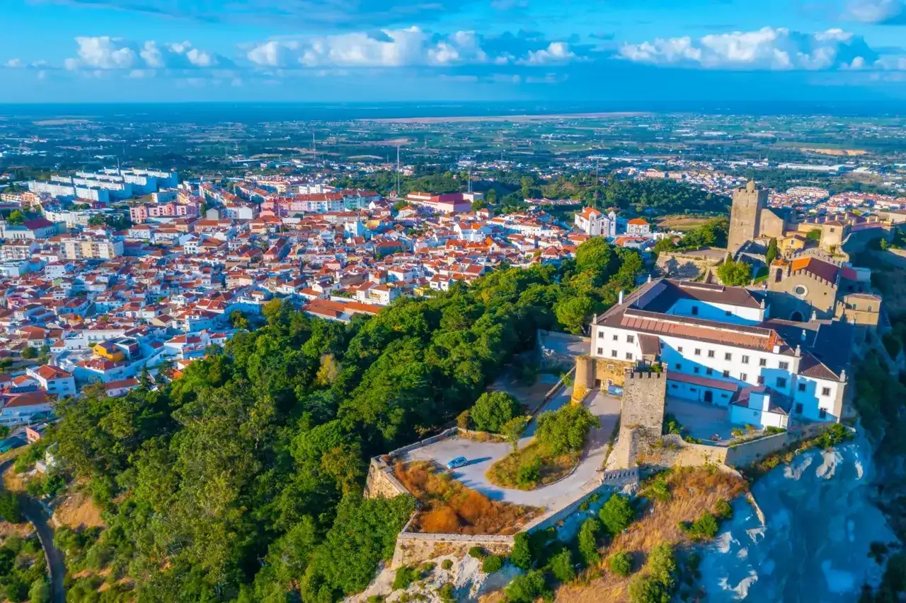 Vista aérea de un castillo y un pueblo con tejados rojos, ideal para unas vacaciones en Portugal.
