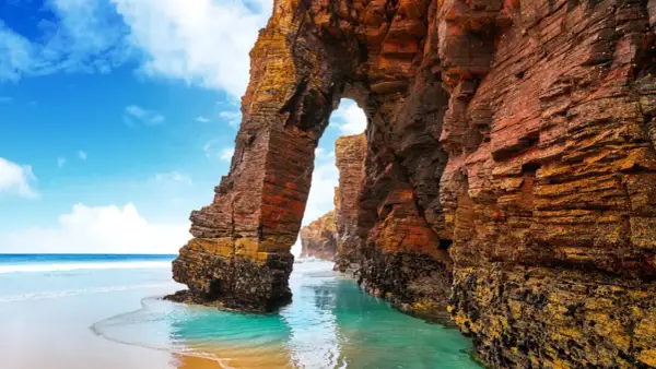 Arco natural en la playa de las Catedrales, un lugar ideal donde viajar en agosto en España.